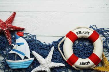 Nautical Sail boat toy model and lifebuoy with blue fishing net top view on wooden background clipart