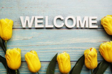 Tahta zemin üzerinde lale çiçeği olan alfabe harflerini hoş geldiniz.