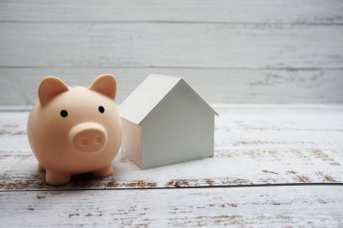 Ahşap arka plan, iş yatırımı ve emlak konsepti üzerine kurulu domuz kumbarası ve ev modeli