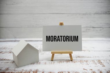 Ahşap arka planda hesap makinesi ve ev modeli ile Moratorium metin iletisi