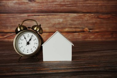 Ahşap arka planda alarmlı ev modeli