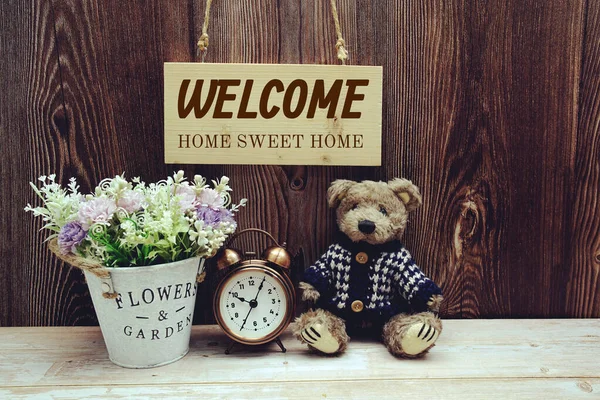 欢迎使用闹钟 花束和玩具熊装饰木制背景的标志 — 图库照片