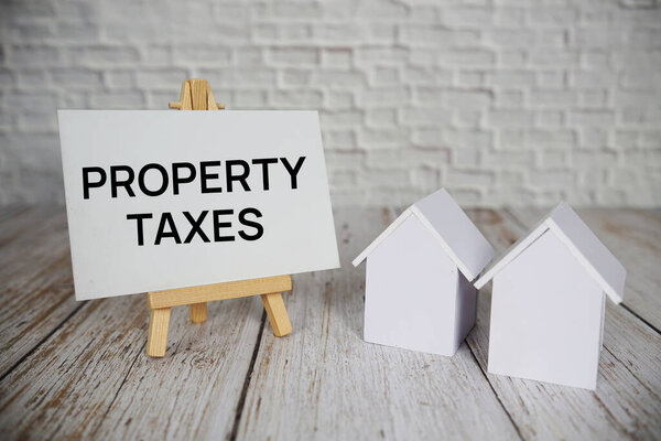 Свойство Налоги текстовое сообщение с калькулятором и модель дома на деревянном фоне