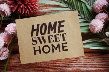 Ahşap arka planda çiçek süslemesi olan evim güzel evim mesajım.