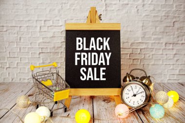 Kara Cuma saati ve ahşap arka planda trollü alışveriş arabası olan kısa mesaj.