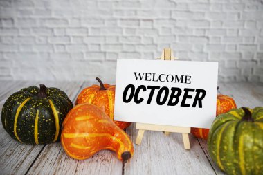 Tahta zemin üzerinde balkabağı süslemesi olan Ekim mesajına hoş geldiniz