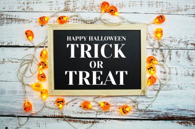 Tahtada LED balkabağı süslemeli şaka mı şeker mi metni tahta zemin üzerinde