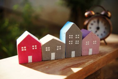 Çalar saat ve ev modeli yeşil arka planlı masada.