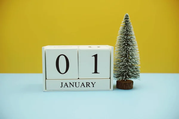 stock image Wooden calendar 1st January with chirtsmas tree on yellow and blue background