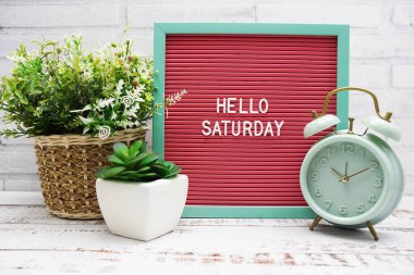 Hello Saturday text on Letter Board with alarm clcok and artificial plant decoration clipart