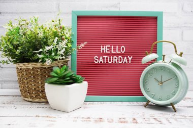 Hello Saturday text on Letter Board with alarm clcok and artificial plant decoration clipart