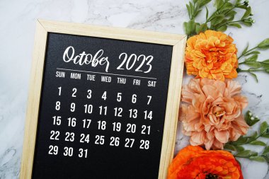 Ekim 2023 aylık takvim mermer arka planda çiçek buketi süslemesi