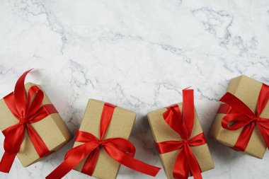 Mermer zemin üzerinde kırmızı kurdele olan hediye kutuları