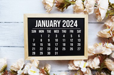 Ahşap arka planda çiçek buketi süslemesi olan Ocak 2024 aylık takvim