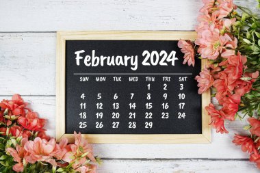 Ahşap arka planda çiçek buketi süslemesi olan Şubat 2024 aylık takvim