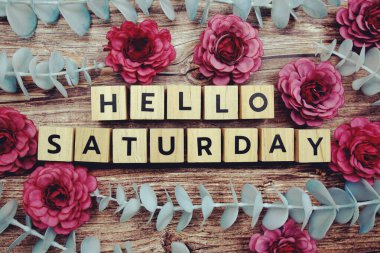 Merhaba Cumartesi alfabesi harfi ve çiçek ahşap arka planda süslenir.