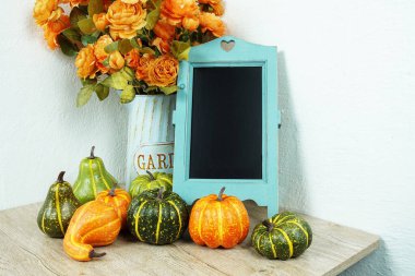 Tahta sehpa yapay çiçekler ve ahşap masa dekorasyonunda balkabağı ile süslenir.