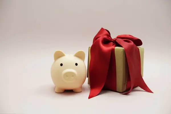 Gift box and piggy saving bank on pink background