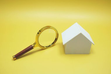 Ev modeli ve büyüteç sarı arka planda izole edilmiş.