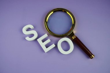 Mor arkaplanda SEO harfleri ve büyüteç üst görünümü