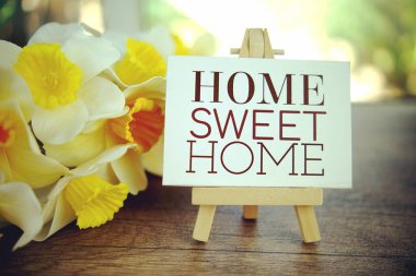 Home Sweet Home mesaj kağıdında ahşap sehpa ve ahşap masa zemininde çiçek süslemesi