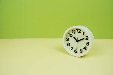 Yeşil ve sarı arkaplanda boşluk kopyası olan beyaz alarm saati