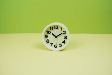 Yeşil ve sarı arkaplanda boşluk kopyası olan beyaz alarm saati