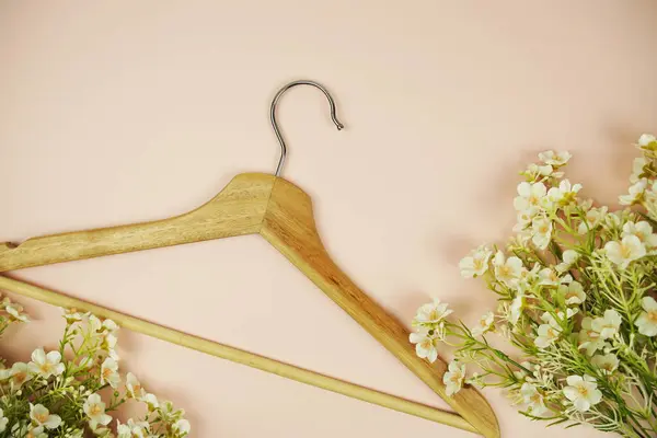 Wooden hanger with flower bouquet and space for copy on pink background