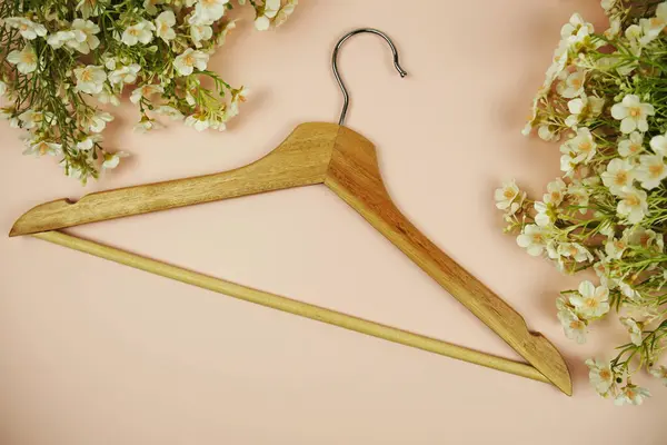 Wooden hanger with flower bouquet and space for copy on pink background