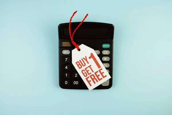 Top view of Buy One Get One Free text on tag sale with calculator flat lay on blue background