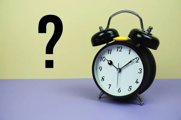 Question mark and alarm clock on yellow and purple background