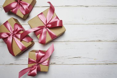 Ahşap arka planda pembe kurdeleli hediye kutuları