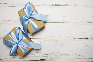 Ahşap arka planda mavi kurdeleli hediye kutuları