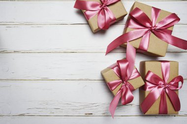 Ahşap arka planda pembe kurdeleli hediye kutuları