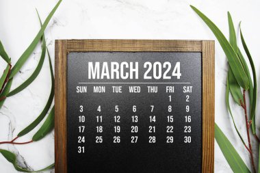 Mart 2024 Aylık takvim mermer arka planda yeşil yaprak dekorasyonu