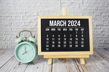 Ahşap zemin üzerinde aylık Mart 2024 takvim ve alarm saati