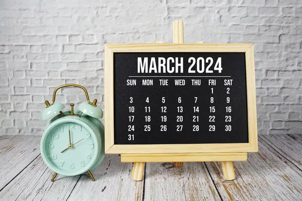 Ahşap zemin üzerinde aylık Mart 2024 takvim ve alarm saati
