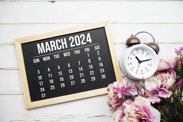 Ahşap zemin üzerinde aylık Mart 2024 takvim ve alarm saati