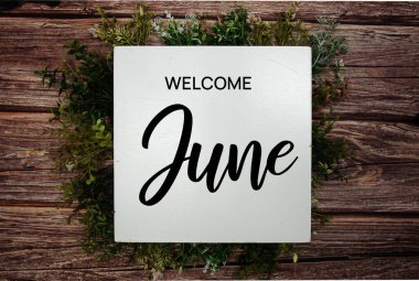 Ahşap arkaplanda yeşil yaprak süslemesiyle Haziran mesajına hoş geldiniz