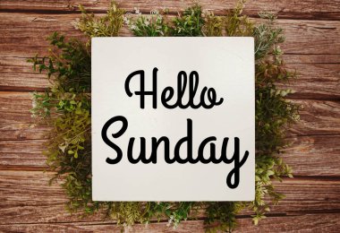 Merhaba Pazar mesajı. Ahşap arka planda yeşil yapraklar var.