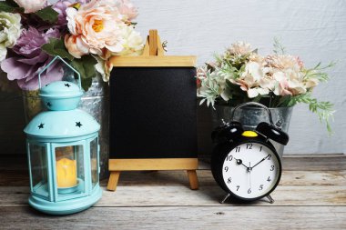 Mavi fener, çalar saat ve çiçek desenli ahşap arka planda Easel modeli.