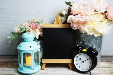 Mavi fener, çalar saat ve çiçek desenli ahşap arka planda Easel modeli.