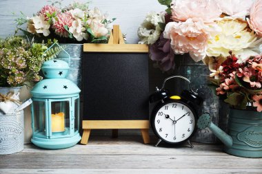 Mavi fener, çalar saat ve çiçek desenli ahşap arka planda Easel modeli.