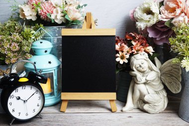 Mavi fener, çalar saat ve çiçek desenli ahşap arka planda Easel modeli.