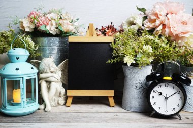 Mavi fener, çalar saat ve çiçek desenli ahşap arka planda Easel modeli.