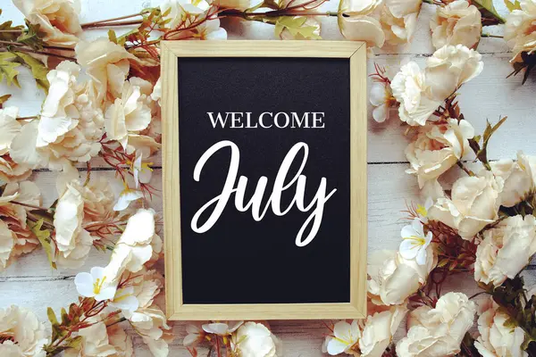 Tahta arka planda çiçek desenli Temmuz mesajına hoş geldiniz.