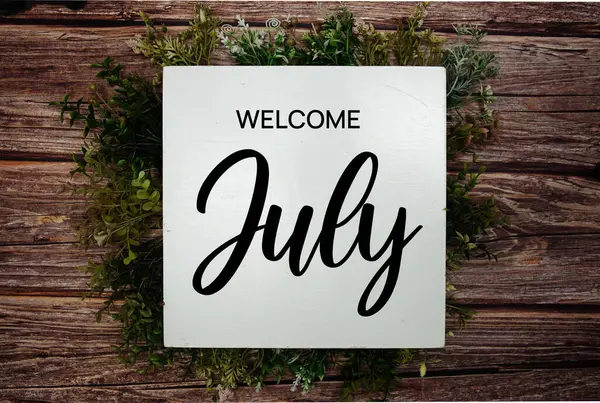 Tahta zemin üzerinde yeşil yaprak süslemesi olan Temmuz mesajına hoş geldiniz