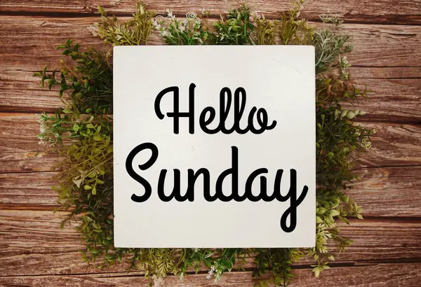 Merhaba Pazar mesajı. Ahşap arka planda yeşil yapraklar var.