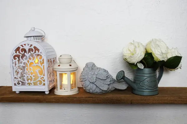 Home decoration accessories white lantern stick with LED candle light and bird statue, flower in metal vase on wooden shelves and white concrete wall