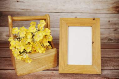 Boş fotoğraf çerçevesi ahşap arka planda çiçek buketi süslemesiyle maket yap